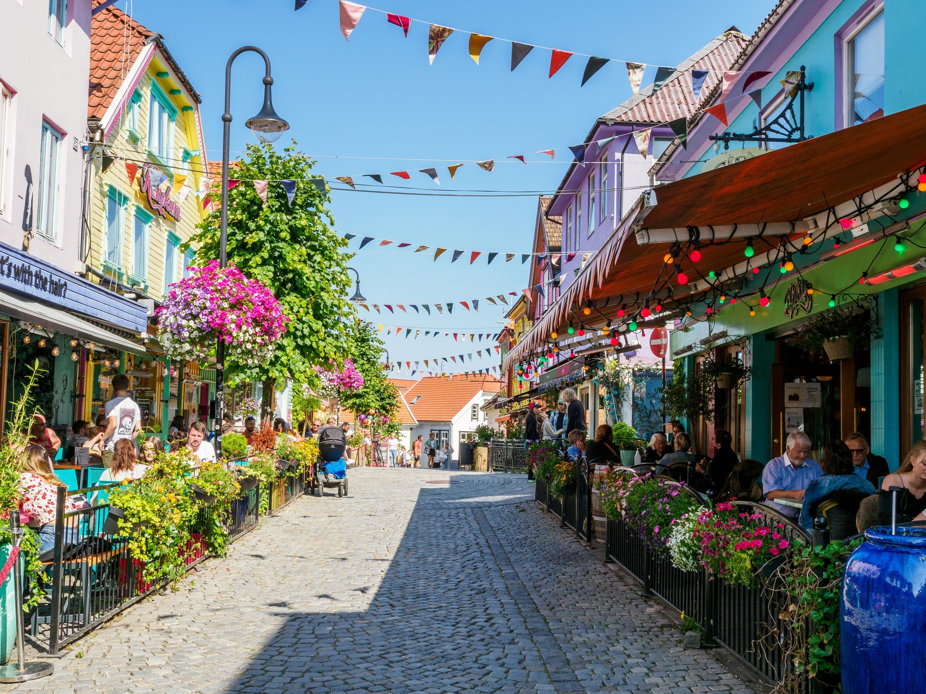 Stavanger, Norway - July 22, 2021: Tourists on historical street in Stavanger old town with multicolor wooden houses.